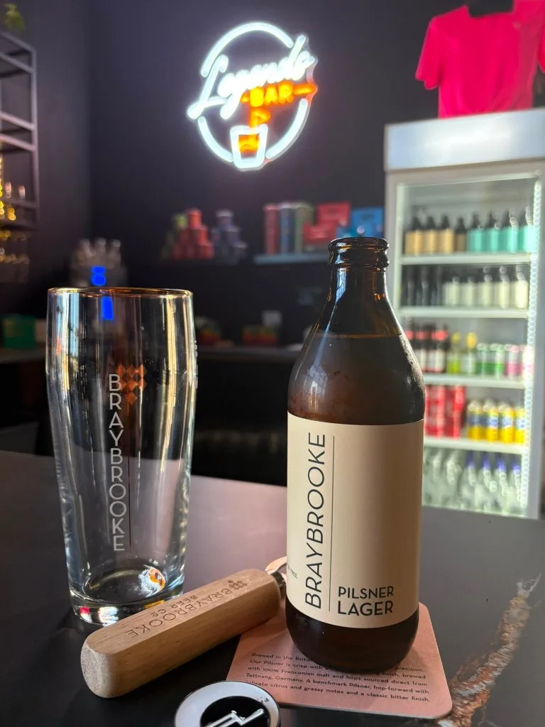 Braybrooke Pilsner bottle and glass at Legends Bar with neon sign