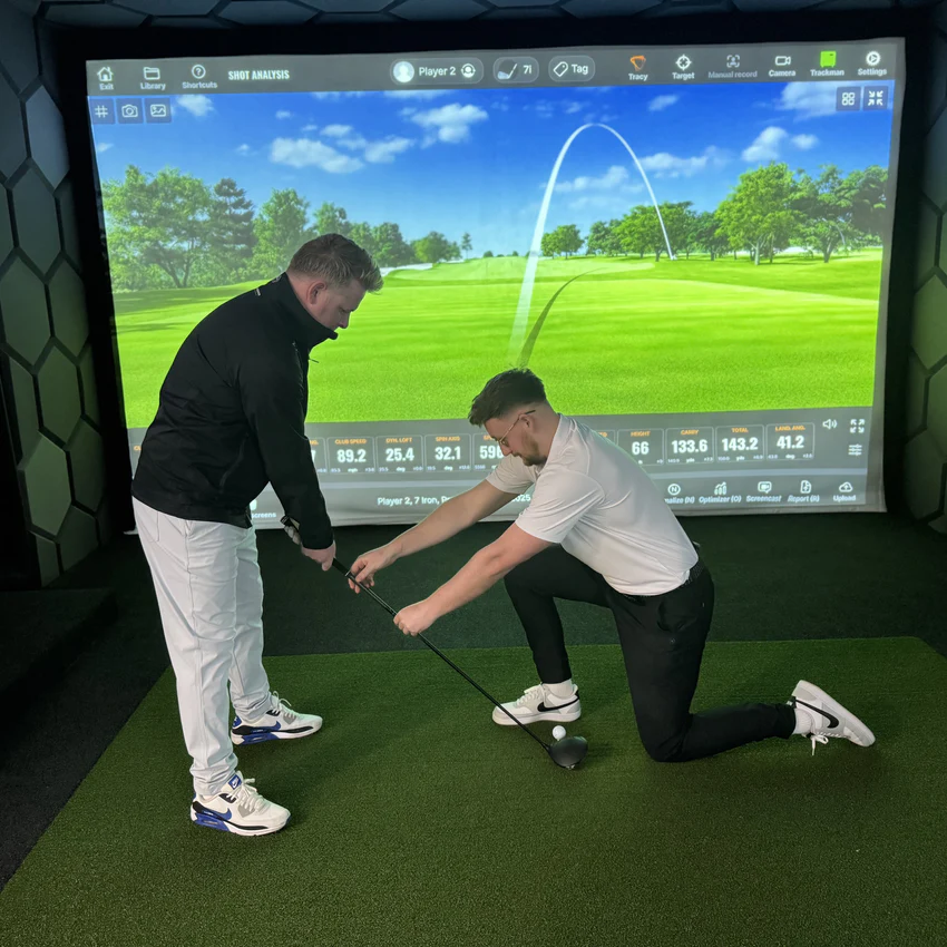 PGA coach delivering a Trackman lesson with live shot analysis on screen
